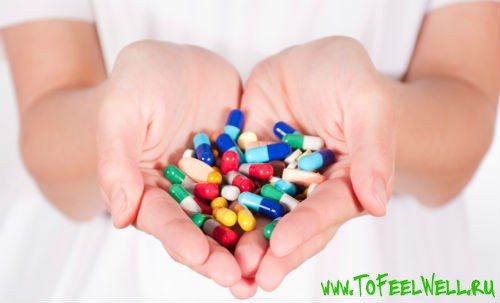 разноцветные таблетки держит в руках