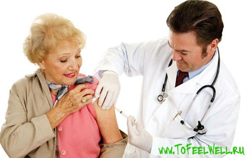 врач делает укол в плечо пожилой женщине