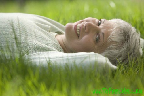 седая женщина лежит на траве и улыбается