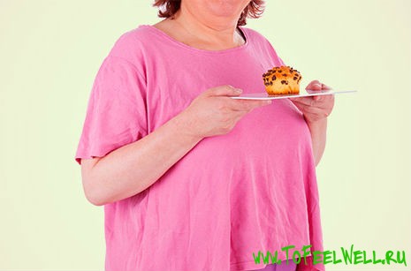 полная женщина держит тарелку с кексом в руках