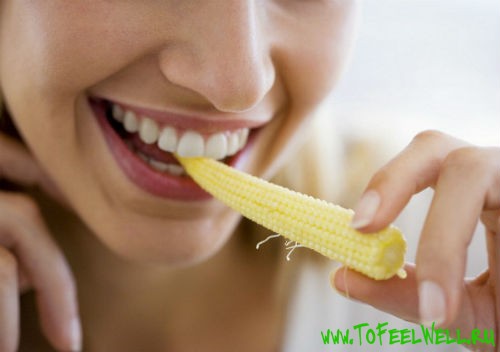 девушка ест кукурузу на белом фоне
